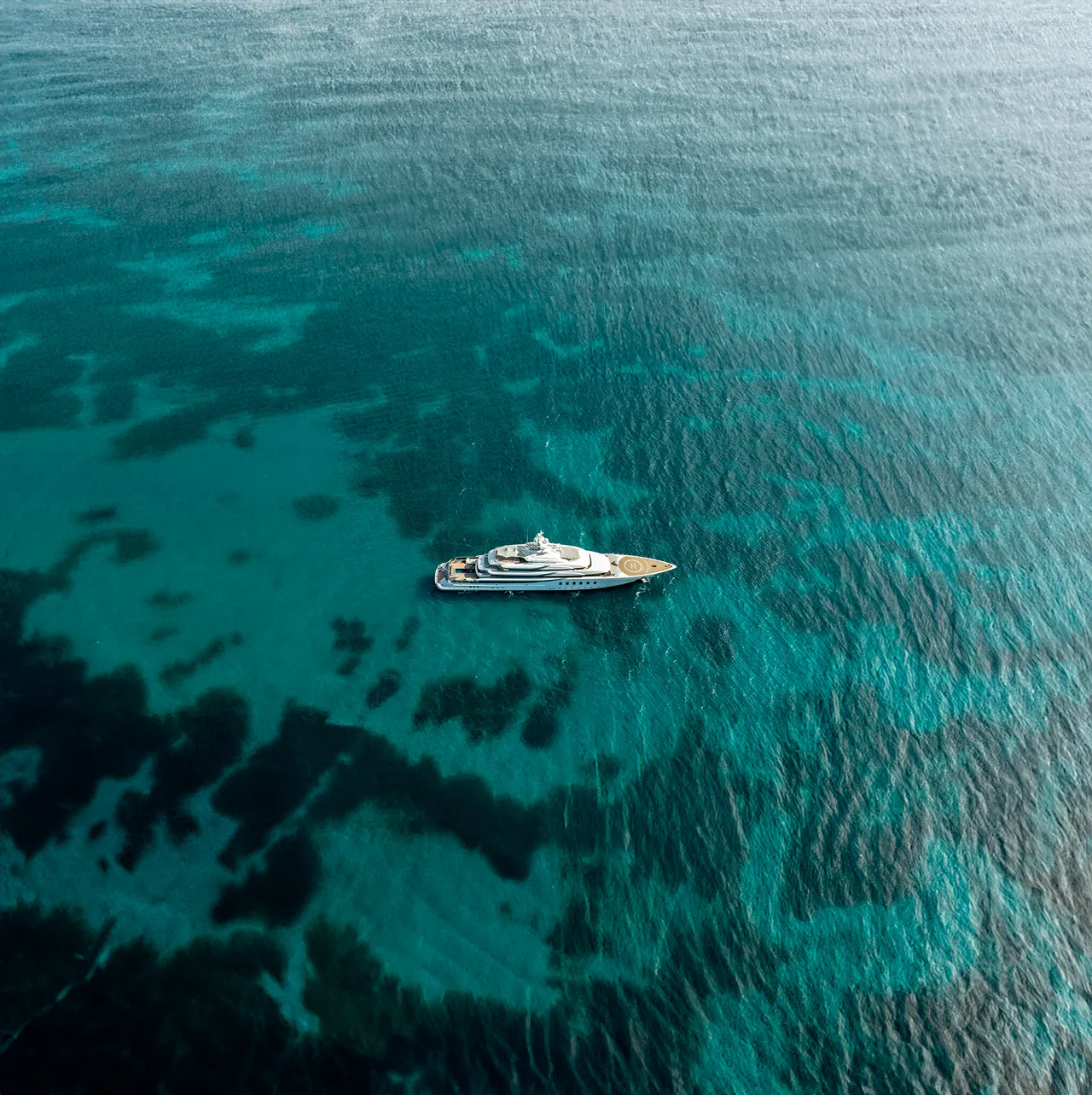 Aerial of a superyacht at anchor on turquoise water